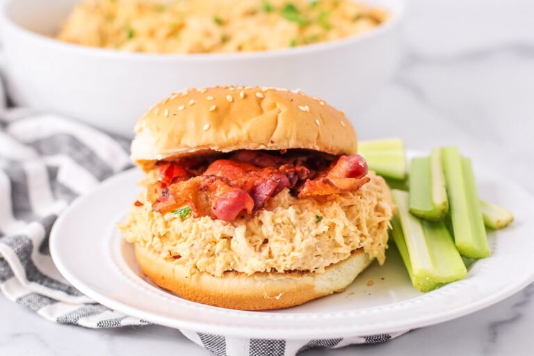 Slow Cooker Crack chicken served on a bun topped with bacon.
