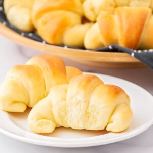 Homemade crescent rolls on white plate.