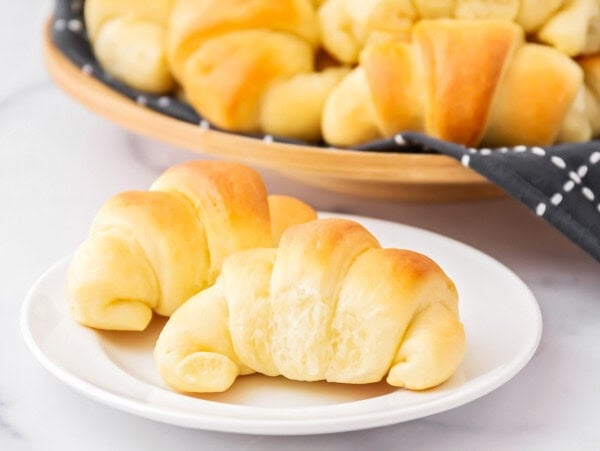 Homemade crescent rolls on white plate.