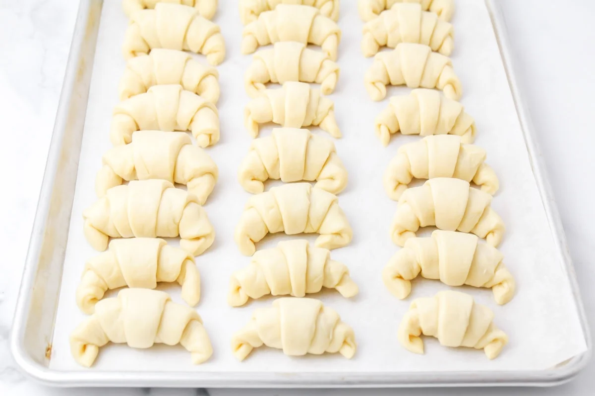 Homemade crescent rolls shaped on baking sheet.