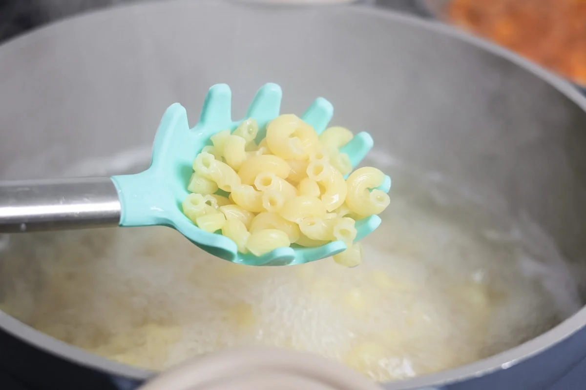 Macaroni being cooked in boiling water.