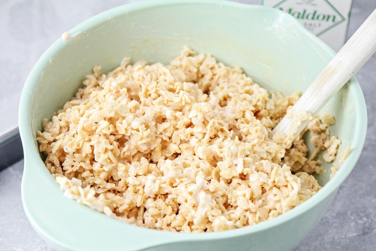 Mixing rice krispies in a mint bowl.