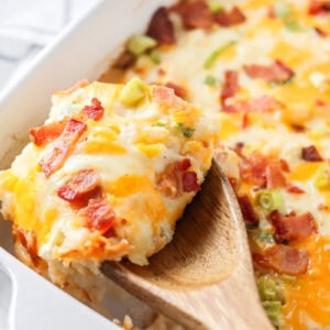 Scooping twice baked potato casserole from a dish.