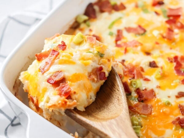 Scooping twice baked potato casserole from a dish.