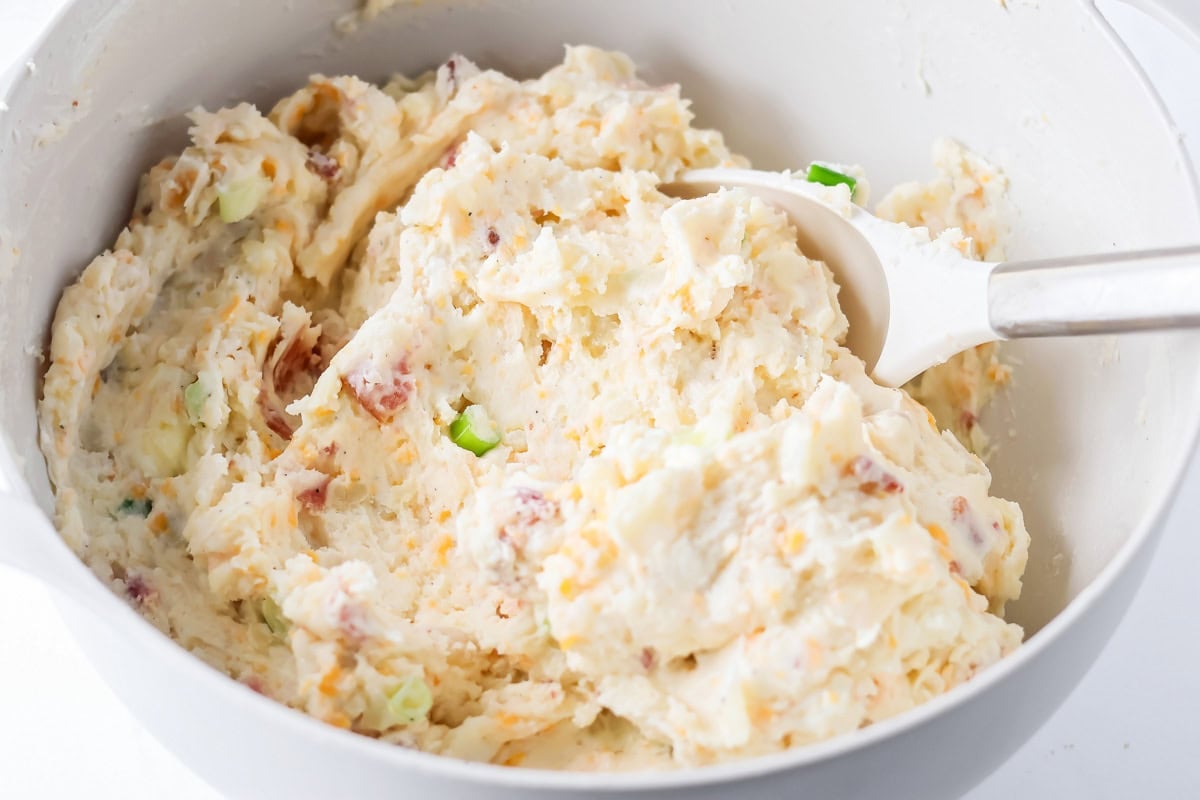 Filling for twice baked potato casserole in a white bowl.