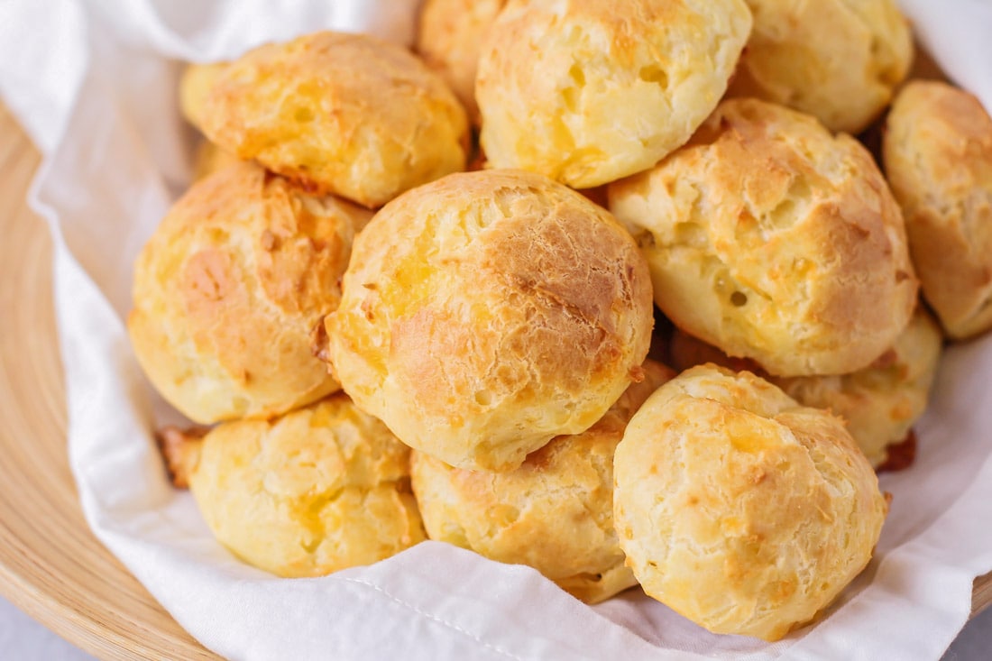 Cheese Puffs piled in a serving bowl lined with a white towel.