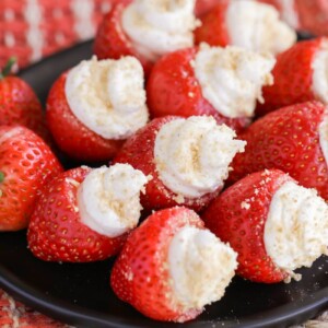 Cheesecake stuffed strawberries on a platter.