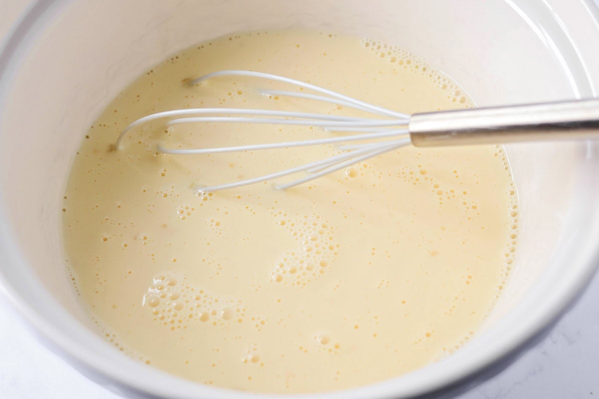 Wet ingredients for Christmas breakfast casserole in a white bowl.