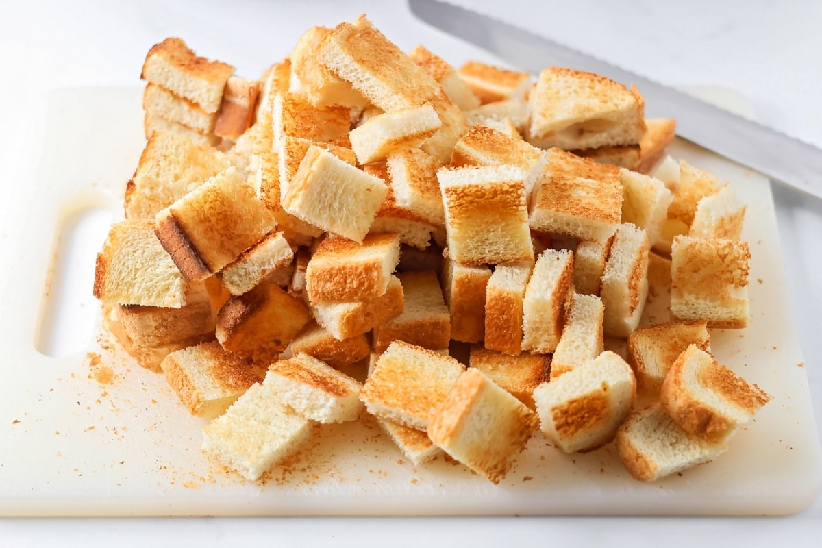 Cubed bread on a cutting board for making Christmas breakfast casserole.