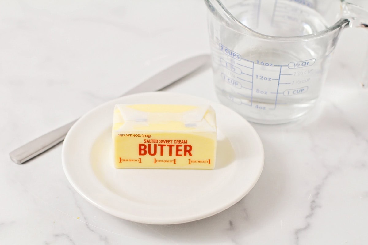 A stick of butter on a white plate.