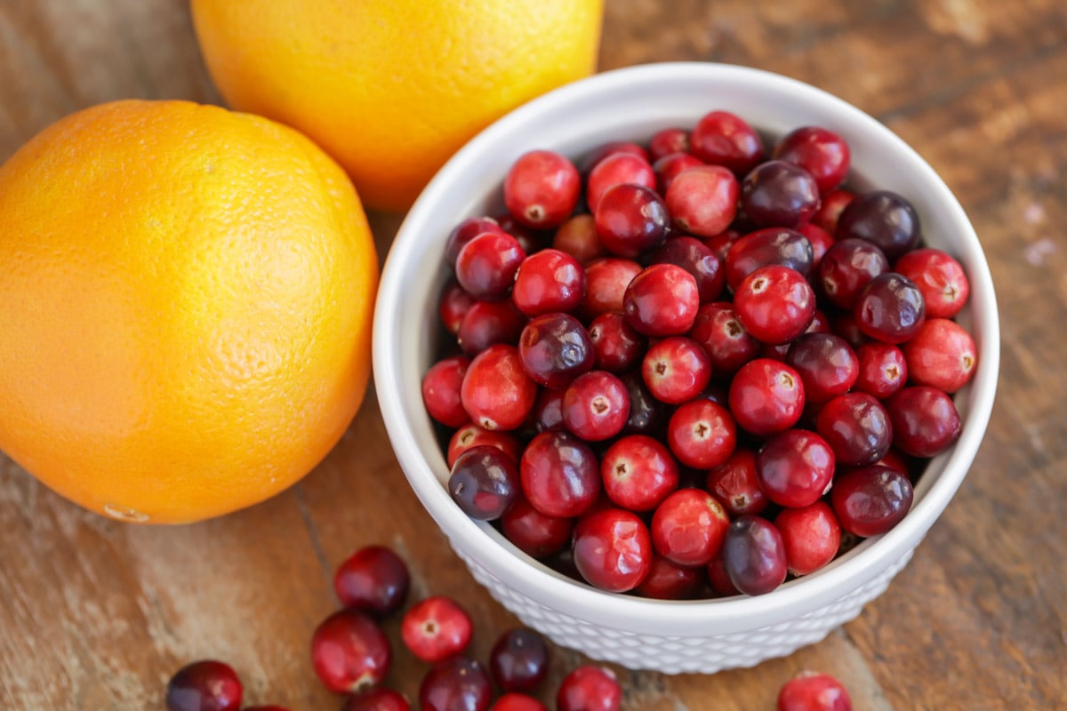 Cranberries and oranges for set on a kitchen table.