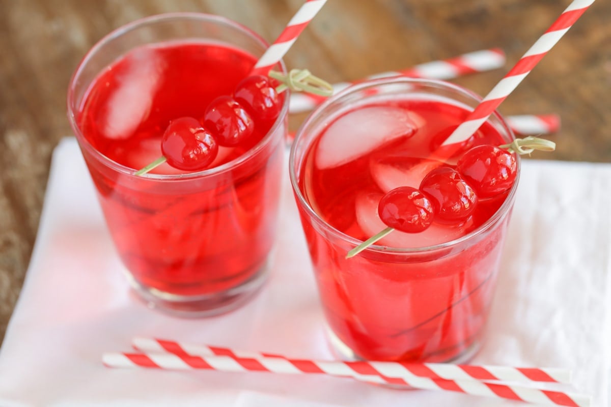 Shirley temples served in glasses with cherries.