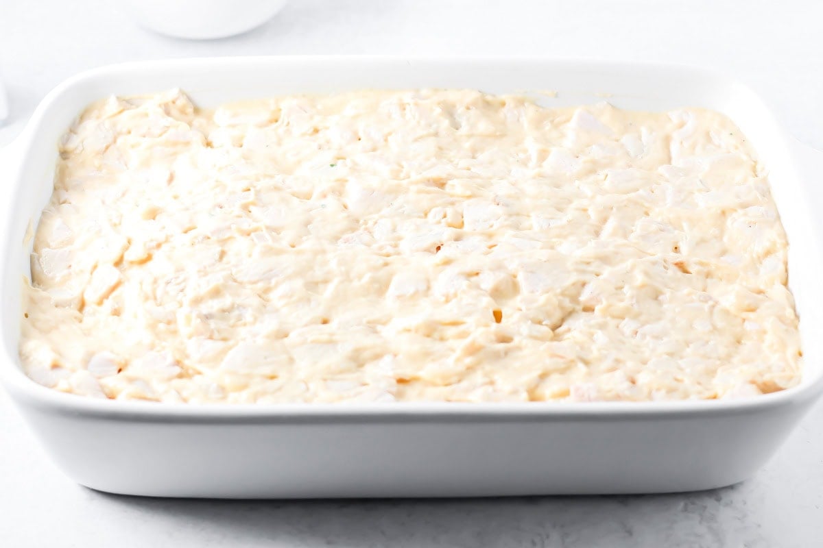Spreading turkey mixture in a baking dish for thanksgiving leftover casserole.
