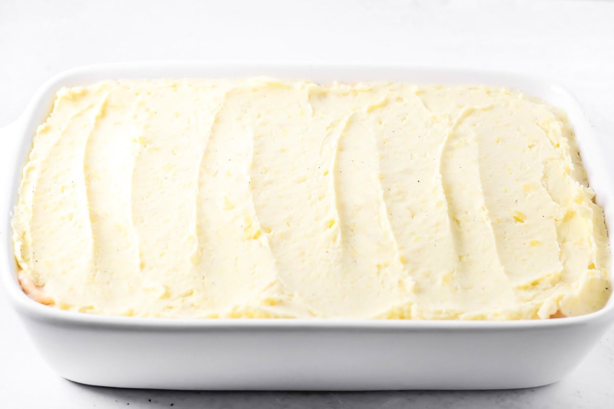 Spreading mashed potatoes on a baking dish of thanksgiving leftover casserole.