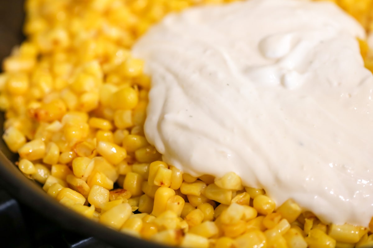 How to make corn esquites by adding cream sauce to corn kernels.