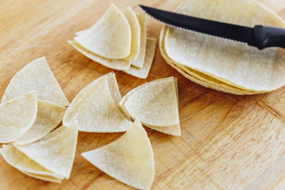 Cutting corn tortillas into quarters.