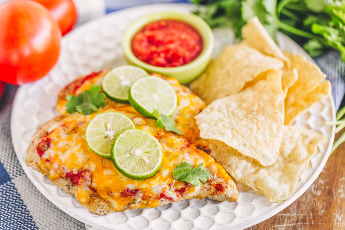 A plate of Mexican chicken served with tortilla chips and salsa.