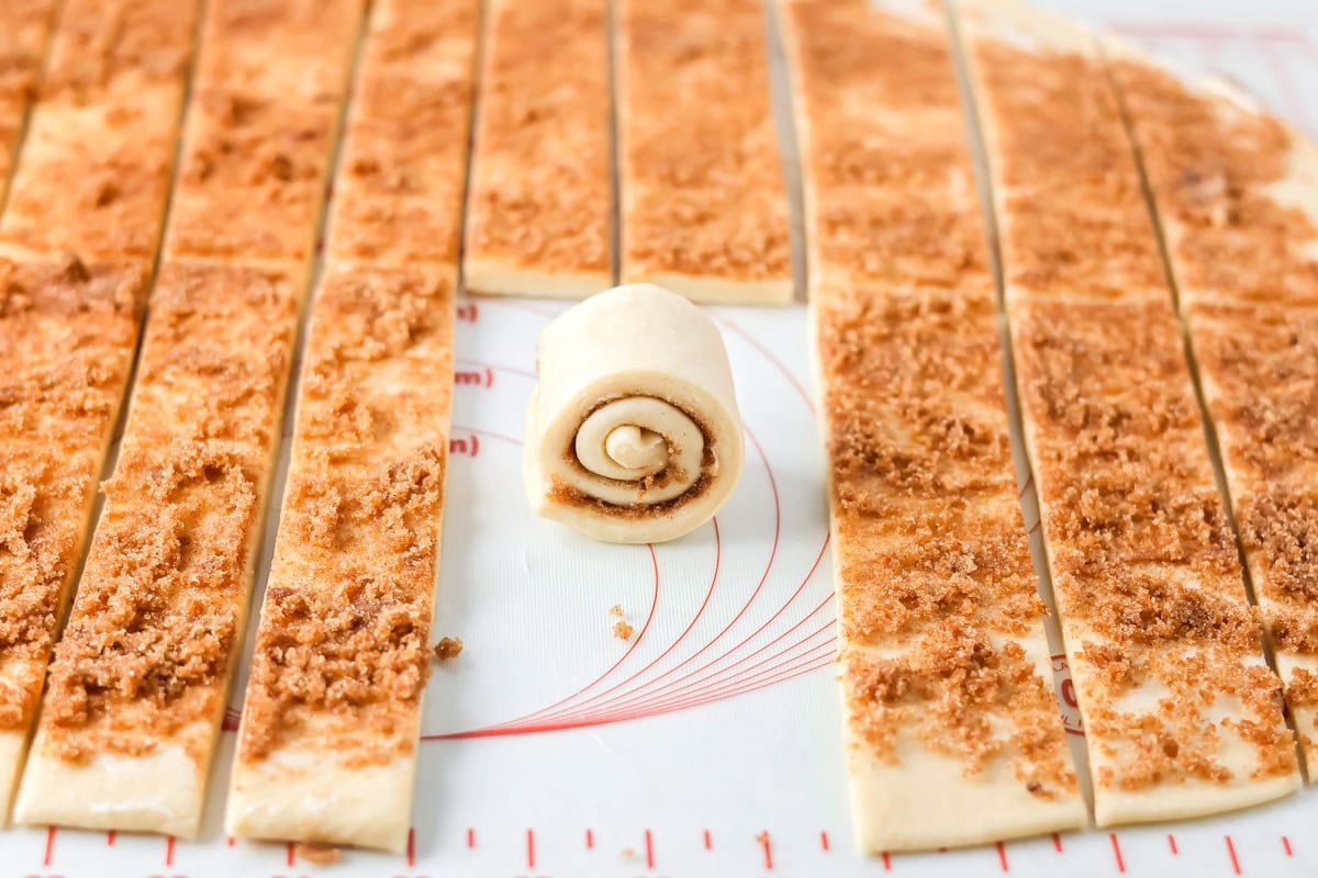 Rolling strips to make mini cinnamon rolls.
