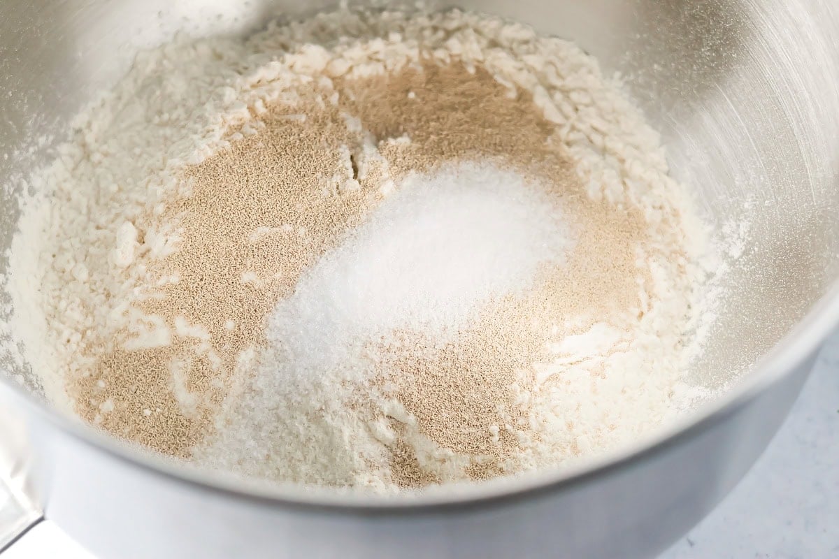 Adding yeast to the dry ingredients for mini cinnamon rolls.