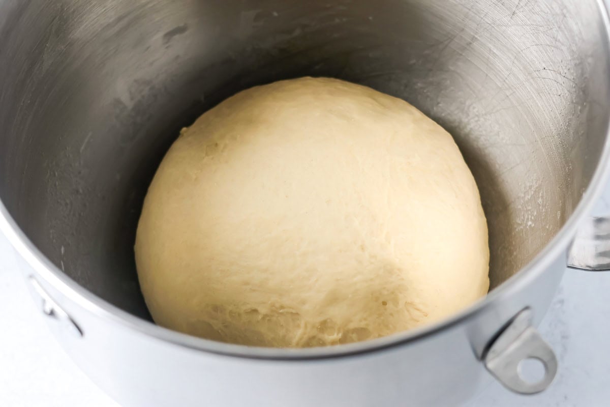Mini cinnamon roll dough rising in a bowl.