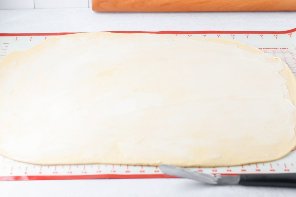 Rolled mini cinnamon roll dough spread with butter.