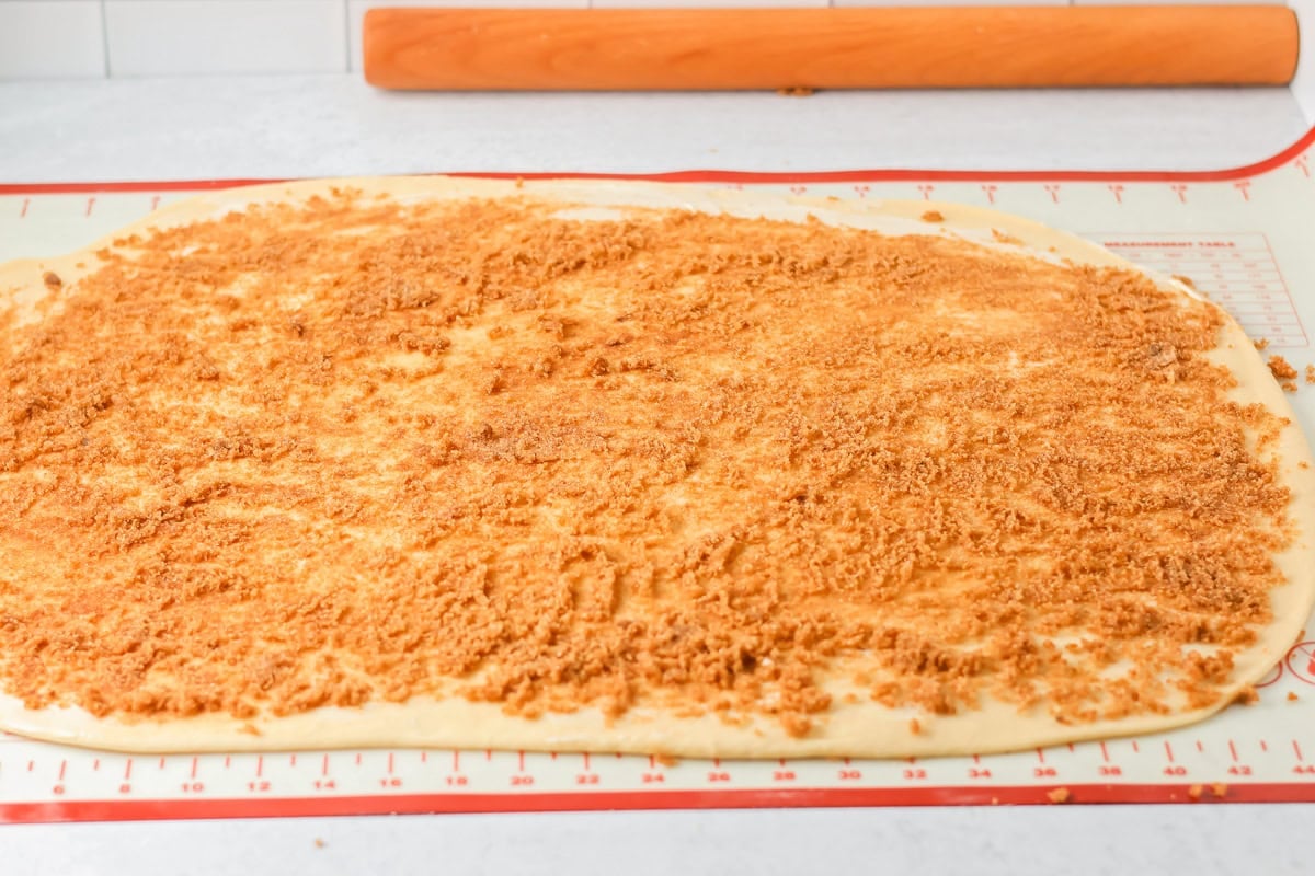 Cinnamon and sugar spread over dough to make mini cinnamon rolls.