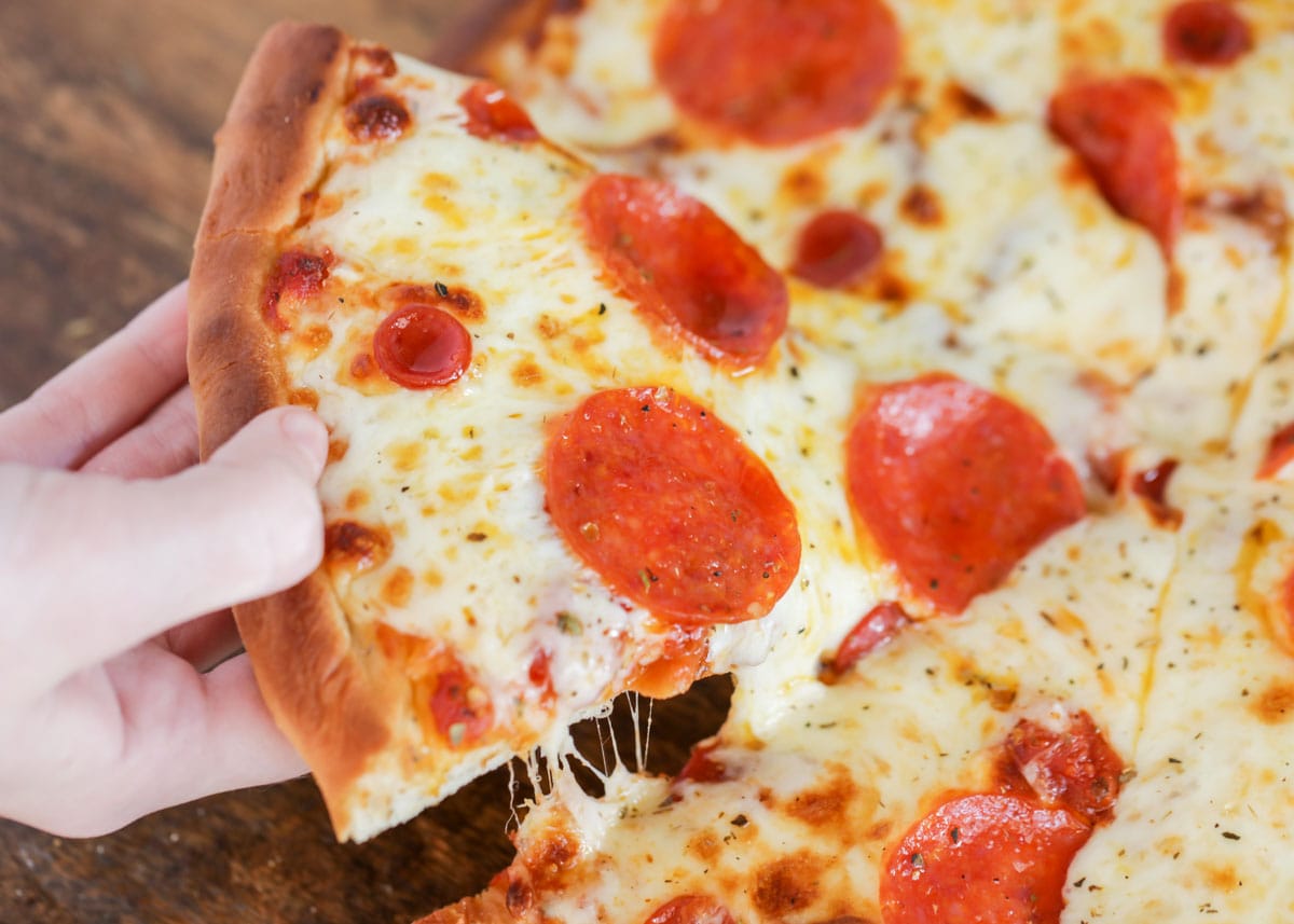 Easy Dinner Ideas - A hand holding a slice of pepperoni pizza.