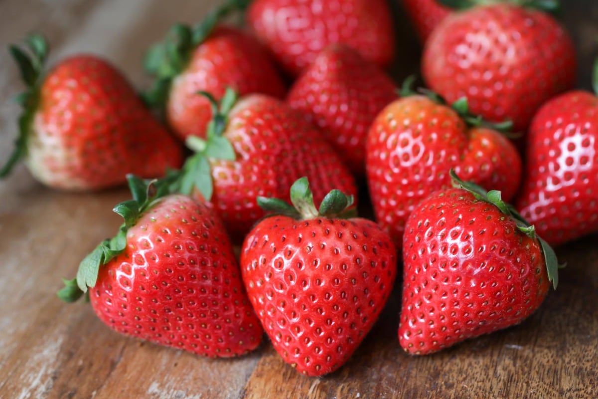 Fresh strawberries on a wooden cutting board. 