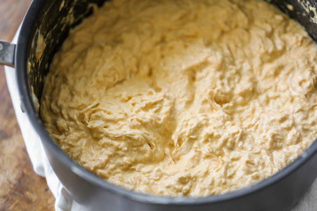 Combining ingredients in a pot for buffalo chicken dip recipe