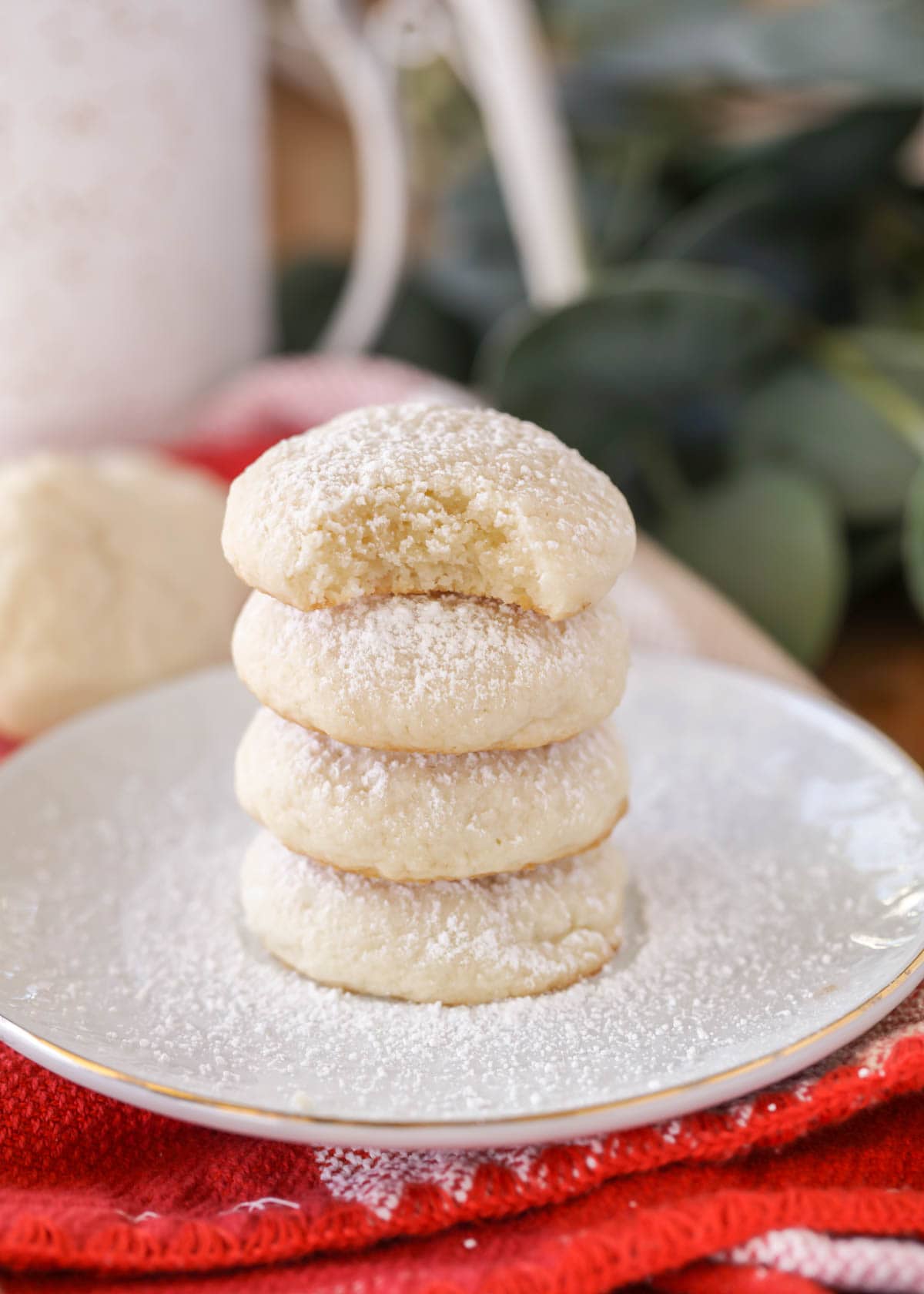 Easy cream cheese cookies stacked on a white plate powdered with sugar