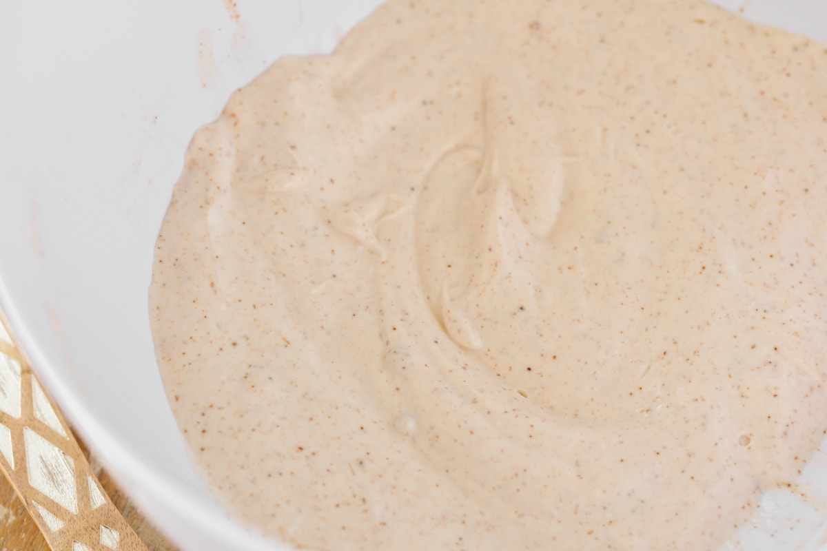 Creamy spiced sauce in a white bowl for Frito Salad.