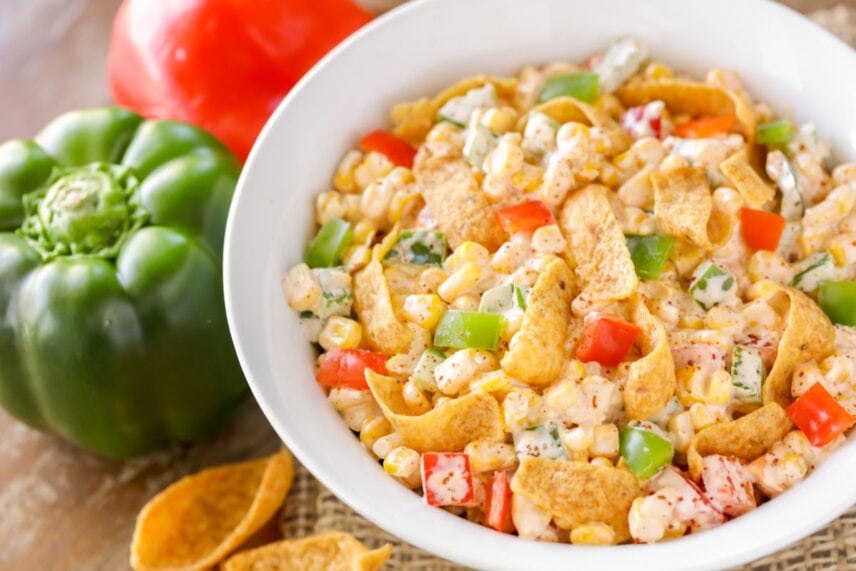 Fresh and tasty frito corn salad is bursting with sweet corn and covered in a perfectly spicy creamy sauce. It is perfectly refreshing. Frito Corn Salad in white bowl.