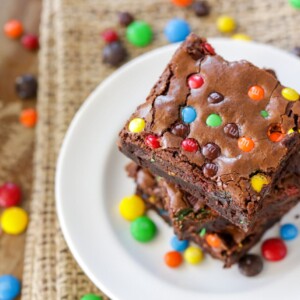 M&M brownies stacked on each other on white plate.