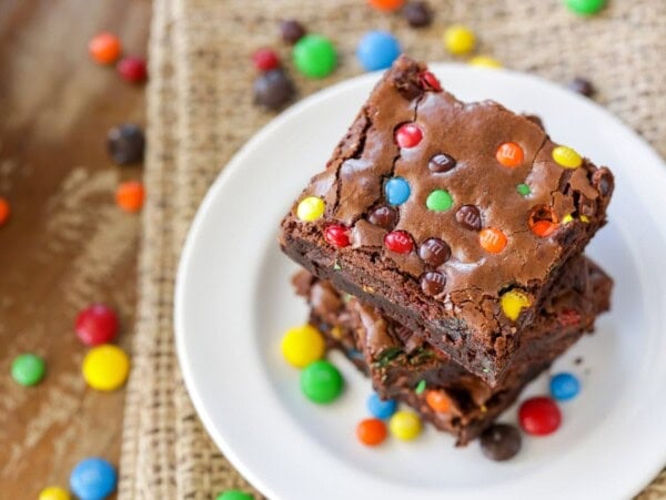 M&M brownies stacked on each other on white plate.