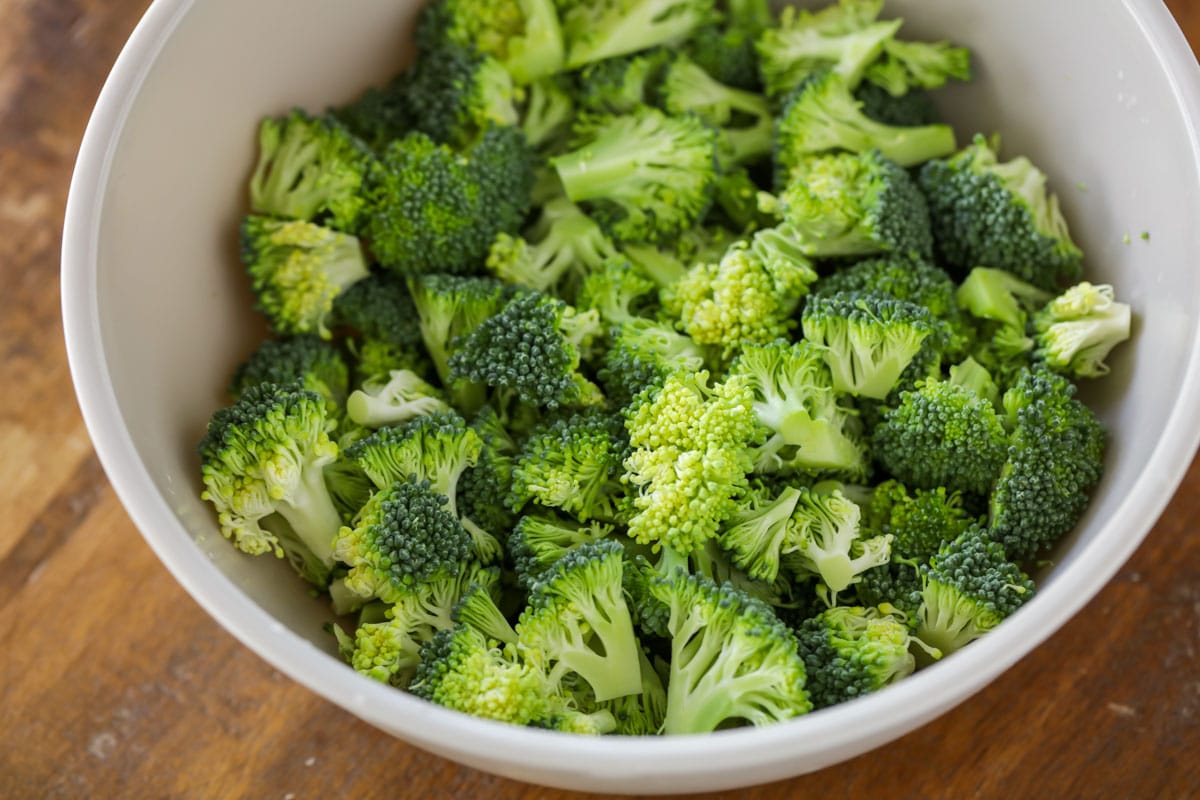 Raw broccoli florets in a white bowl. 