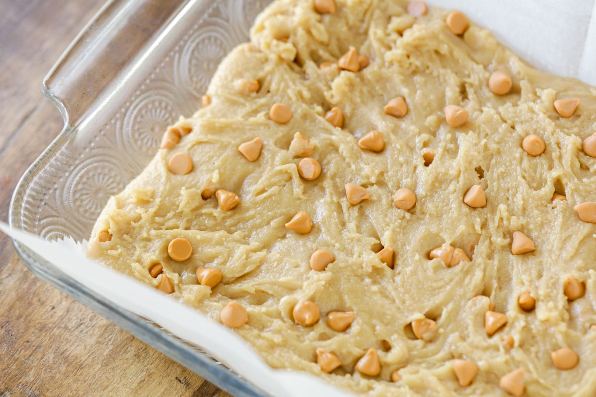 batter covered with butterscotch chips in a glass baking dish