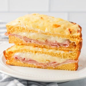 Croque Monsieur recipe cut in half and stacked on each other on white plate.