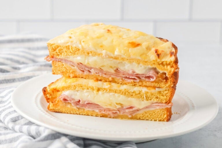Croque Monsieur recipe cut in half and stacked on each other on white plate.