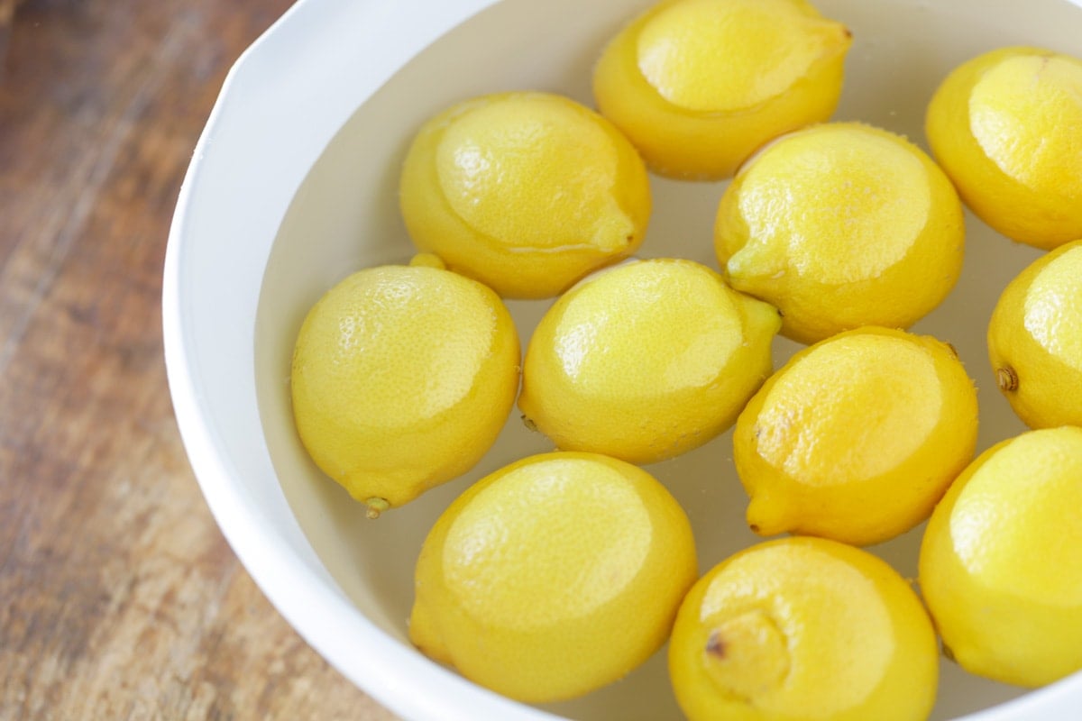 Lemons soaking in a bowl of hot water.