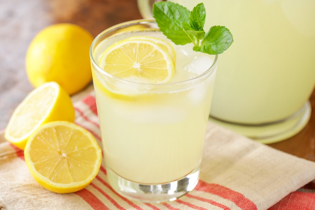 Fresh lemonade in a glass, garnished with lemon slices and mint. 
