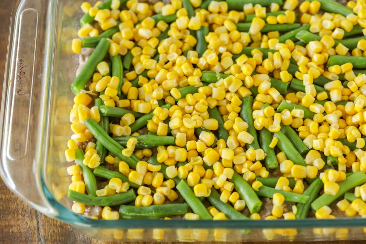 Layers of green beans and corn in a baking dish.