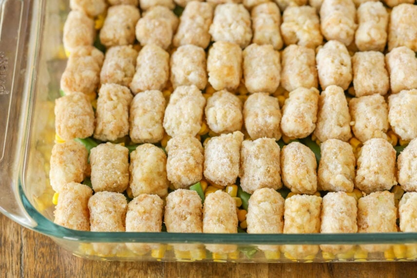 Homey & delicious hamburger tater tot casserole is layered with flavors everyone will love! It is kid-friendly, easy, and freezes perfectly! Tater tots layered on veggies and ground beef in a baking dish.