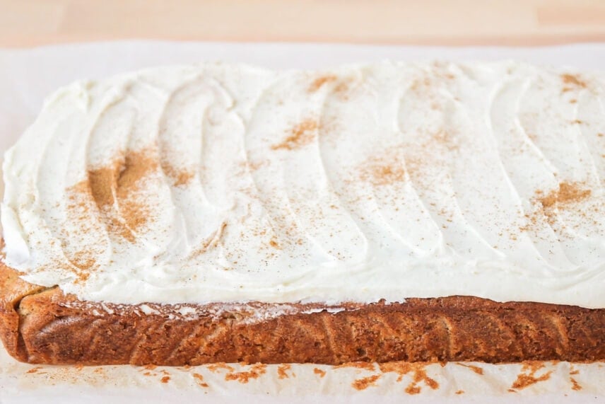 Frosted banana bread brownies on parchment paper.