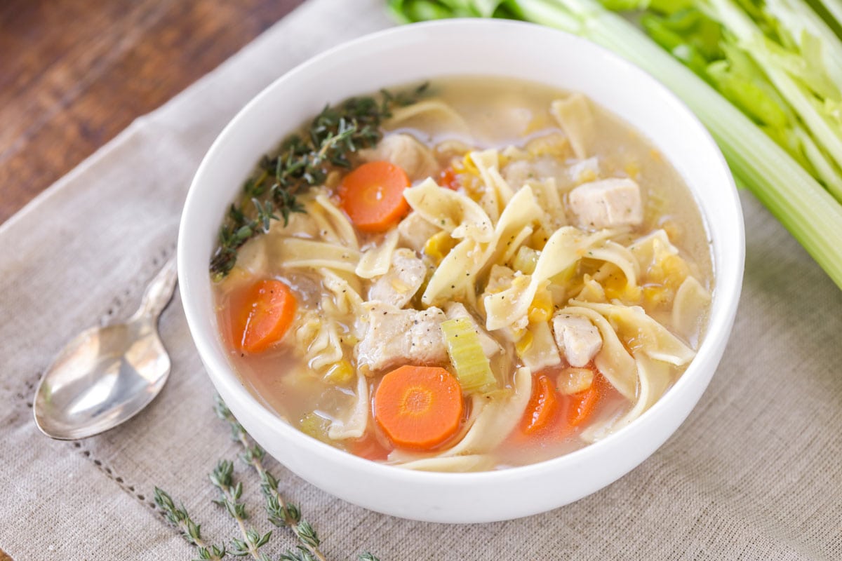 Healthy Soup Recipes - Chicken Corn Soup in a white bowl garnished with a sprig of rosemary.