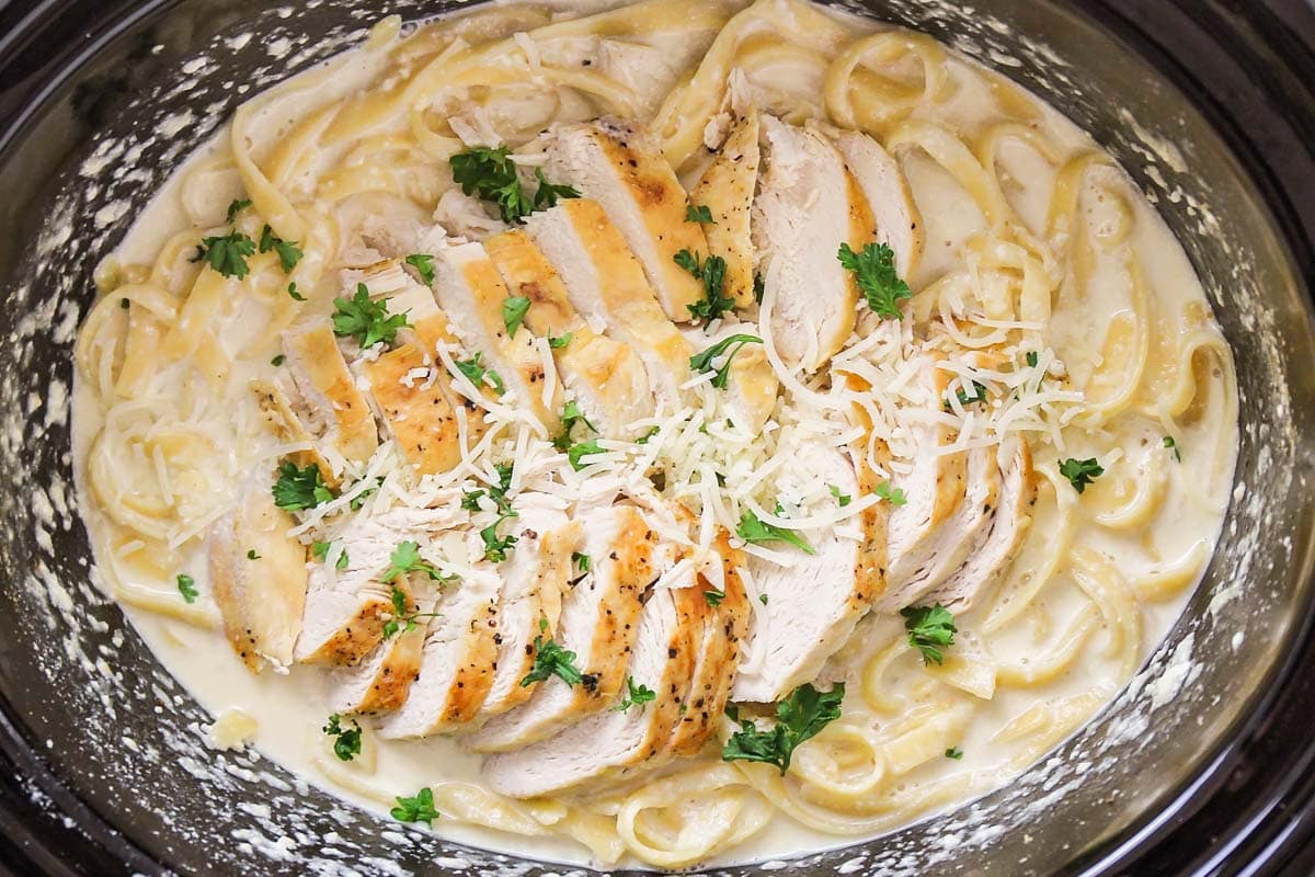 Crockpot chicken alfredo topped with parsley and parmesan cheese.