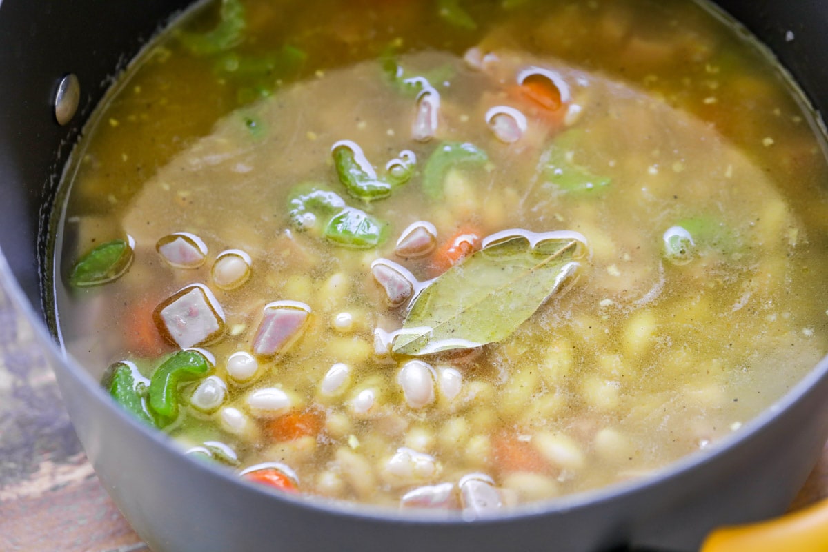 Ham, beans, and veggies in broth in a large pot