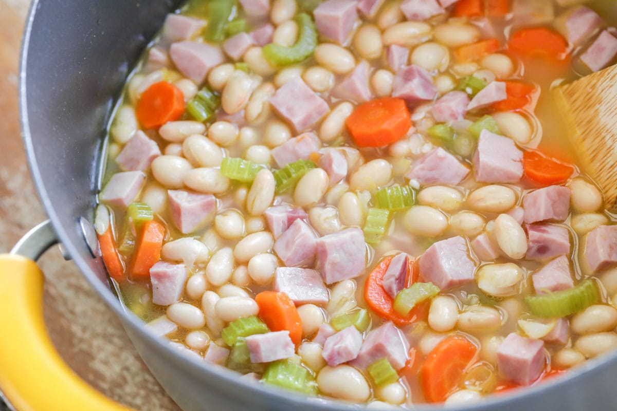 Cooked ham, bean, carrots, and celery in a pot