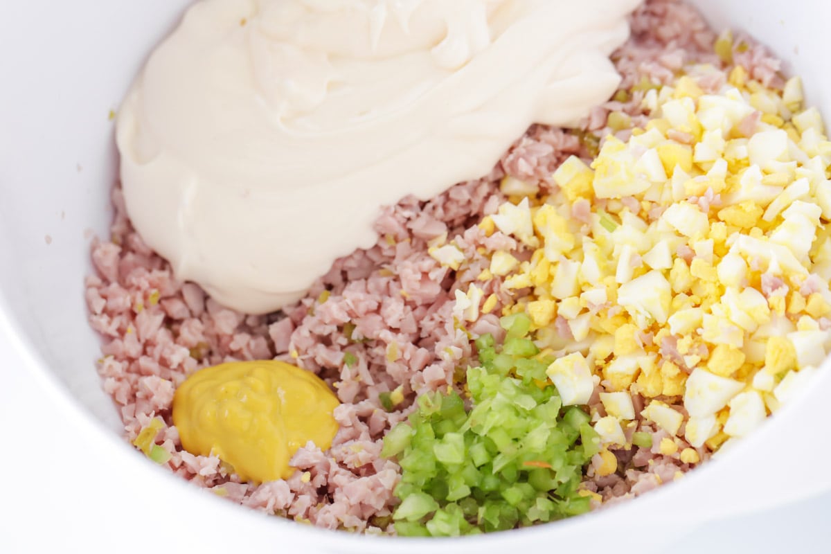 chopped ham, celery, and eggs in a bowl with mayo and mustard