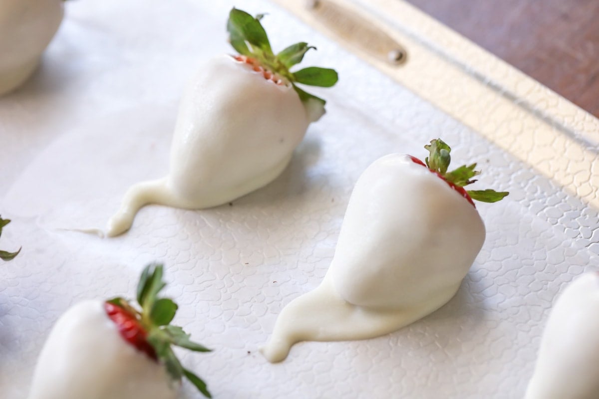 white candy coated strawberries on wax paper