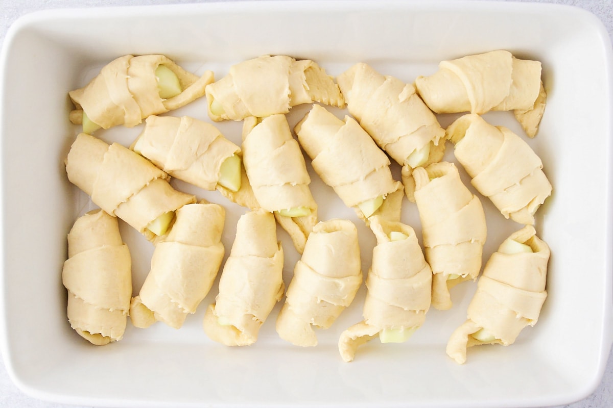 Apple dumplings made with crescent rolls inside a white casserole dish